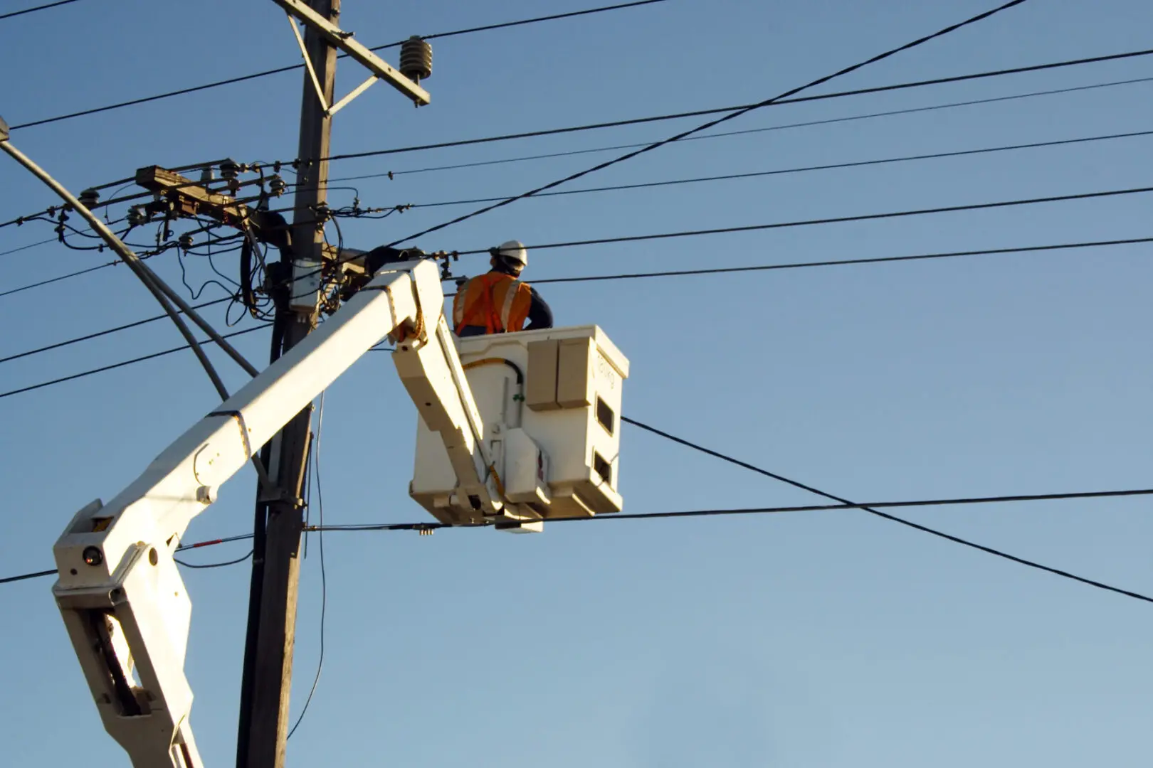 A man in a cherry-picker working on power lines.