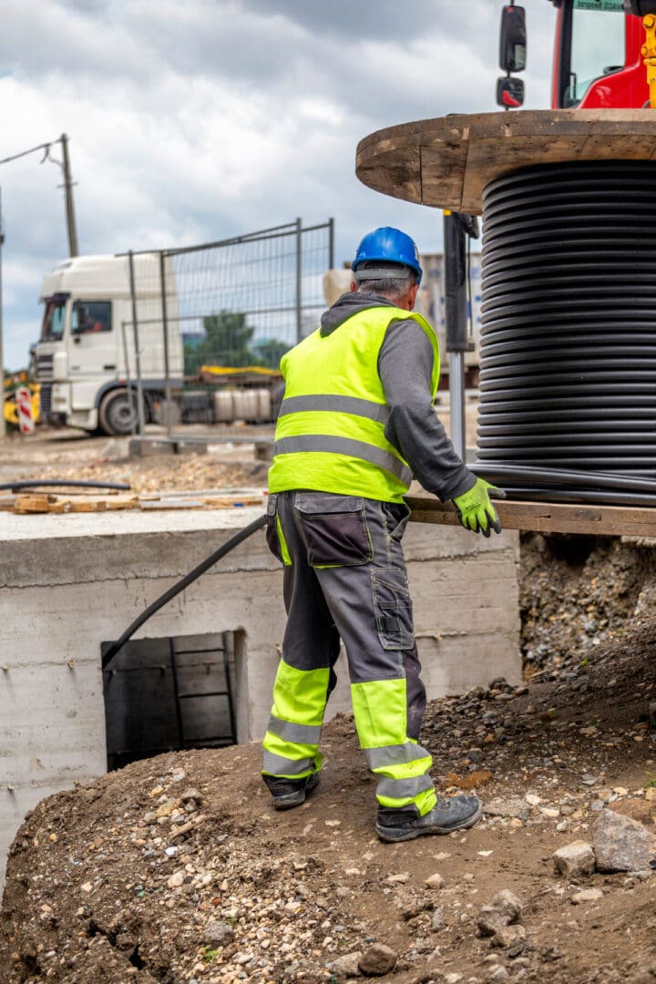 A construction worker is using a long handled tool.