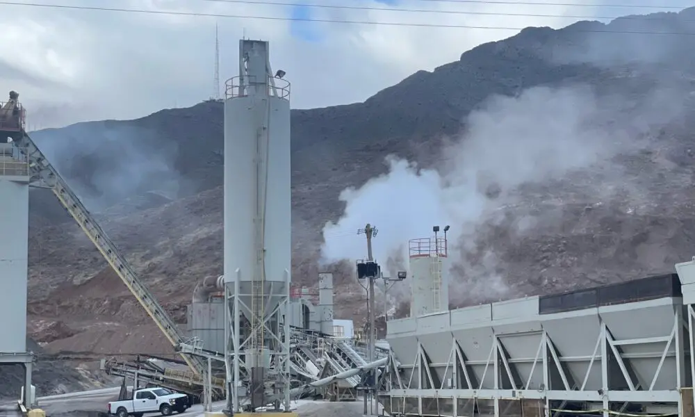 A cement plant with smoke coming out of the chimney.