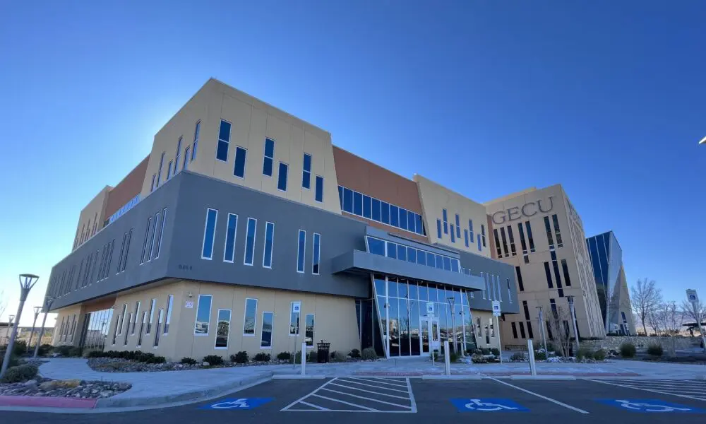 A large building with many windows and a parking lot.