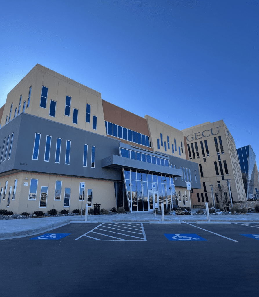 A large building with many windows and lots of parking spaces.