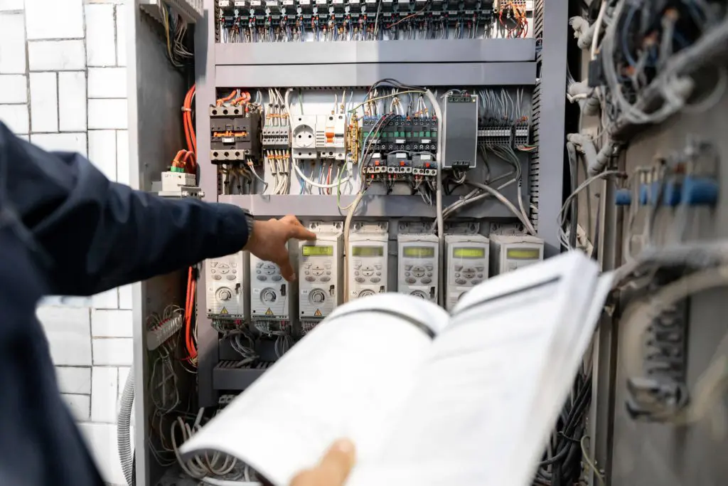 A person is looking at an electrical panel.